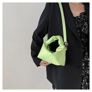 Detail of mint green PU crossbody bag with pleated handle and fashion tag on black blazer