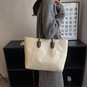 Minimalist large capacity tote bag with brown straps shown from a side shoulder view