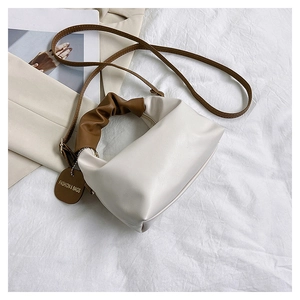 Detail of cream leather shoulder bag with brown pleated handle and fashion tag