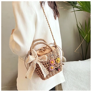 Detail of handmade straw crossbody bag with lace bow and daisy floral accents