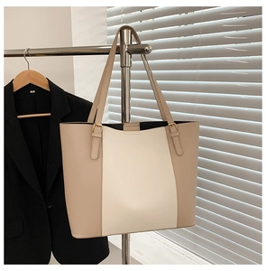 Detail of two-tone beige tote bag showing gold adjustable buckles and PU leather texture