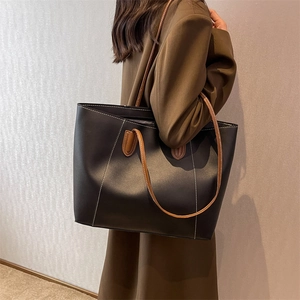 Minimalist black leather tote bag with brown straps and white stitching for women