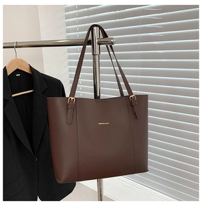 Detail of dark coffee leather tote bag with gold buckle straps and fashion logo text