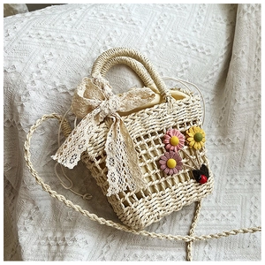 Detail of straw handbag with woven flowers, ladybug charm, and lace bow decoration