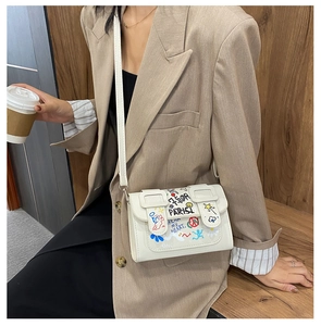 Détail d'un sac bandoulière blanc avec graffitis et imprimés artistiques colorés