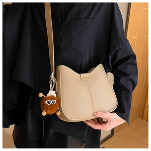 Detail of khaki leather bucket bag with fashion metal plate and plush monster charm