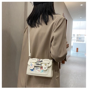 Détail d'un sac bandoulière en cuir blanc avec des graffitis colorés dessinés à la main