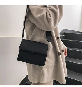 Detail einer minimalistischen matten schwarzen Umhängetasche mit breitem Nylon-Schultergurt