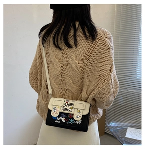 Gros plan d'un sac bandoulière contrasté avec des graffitis de rue et motifs colorés