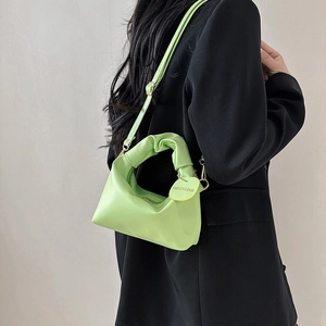 Lime green minimalist crossbody bag with pleated handle and adjustable strap on model