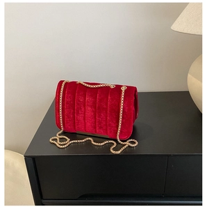 Détail du sac bandoulière en velours rouge avec surpiqûres et chaîne dorée