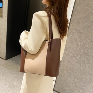Fashion large-capacity tote bag in brown and beige contrast stitching worn by a model