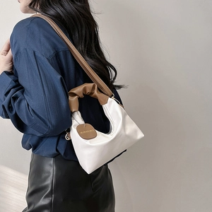 Minimalist white crescent shoulder bag with brown handle and pleated texture design