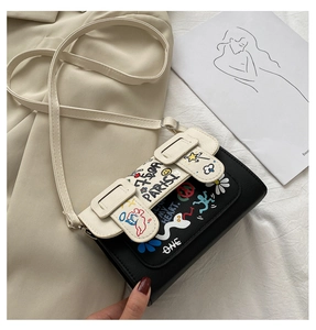 Détail d'un mini sac messager avec motifs graffiti artistiques et design contrasté