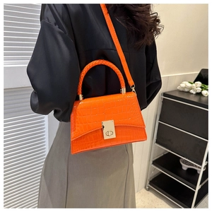 Bright orange tote bag with crocodile texture and woven handle shown on shoulder
