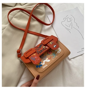 Détail des motifs graffiti artistiques et du cuir synthétique grainé sur le sac bandoulière