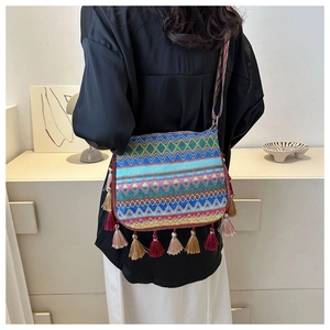 Bohemian woven crossbody bag with colorful wavy patterns and long tassels on model