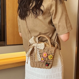 Handmade straw handbag with lace bow and floral details shown on a female model