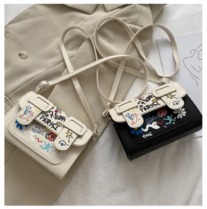Détail de mini sacs bandoulière blancs et noirs avec graffitis colorés et boucles