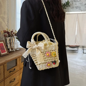 Beige woven bucket bag with lace bow and floral accents, crossbody style for women