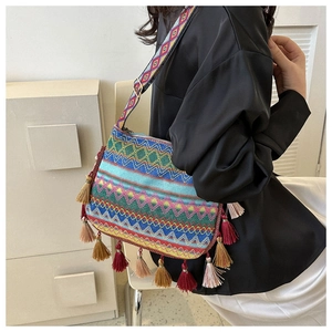 Close-up detail of ethnic woven tote bag with colorful fringe tassels and shoulder strap