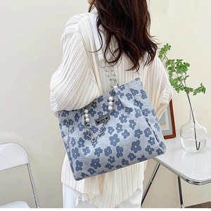 Détail du cabas à fleurs bleues avec chaîne de perles et bandoulière métallique