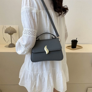 Chic grey minimalist flap handbag with gold wavy buckle and slim shoulder strap