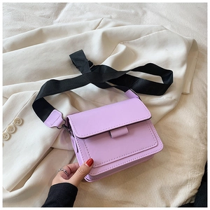 Detail der lila PU-Leder-Tasche mit breitem schwarzem Gurt auf beigem Blazer