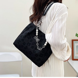Détail du sac cabas jacquard noir avec chaîne perlée et logo en métal fashion