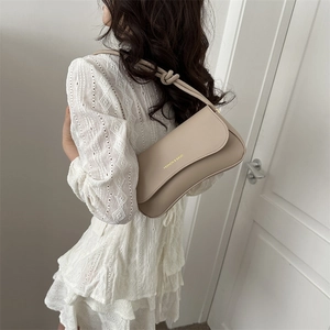 Beige faux leather baguette shoulder bag with knotted strap and gold fashion lettering