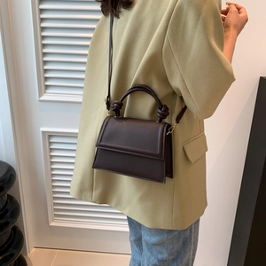 Sac bandoulière minimaliste en cuir mat marron foncé avec poignée ronde et nœuds