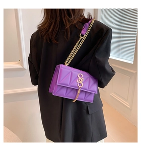 Detail of purple quilted leather crossbody bag with gold tassel and chain strap