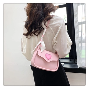 Detailansicht einer rosa Herz-Schultertasche mit einem Seidenschal am Riemen getragen