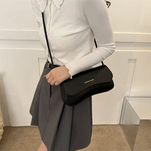Minimalist black matte leather shoulder baguette bag shown on a model outfit