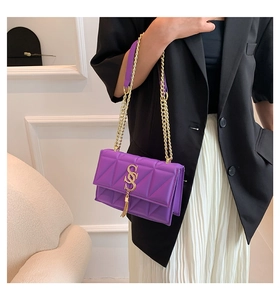 Detail of purple quilted shoulder bag with gold metal S-buckle and tassel pendant