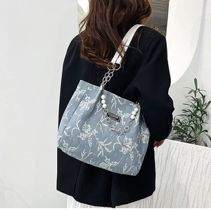 Détail du sac cabas en toile avec motif floral et accessoire de chaîne en perles élégant