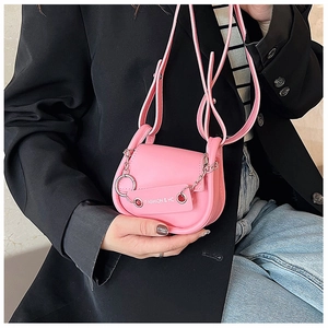 Gros plan d'un sac selle en cuir rose avec chaîne argentée et étiquette de mode sur mannequin