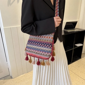 Bohemian woven crossbody bag with geometric patterns and long fringes on a model