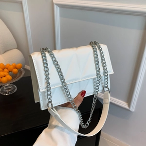 Sac bandoulière matelassé blanc avec chaîne argentée présenté dans un intérieur chic