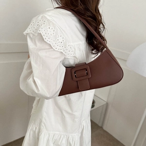 Dark brown leather crescent underarm bag with decorative buckle on a model