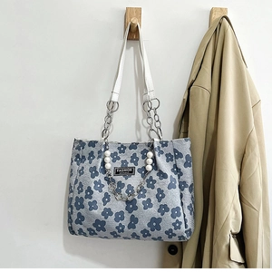 Détail du sac cabas floral en toile bleue avec accents de perles et double poignée