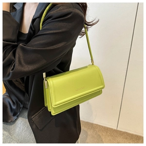 Side view of avocado green rectangle shoulder bag with brand logo shown on a model