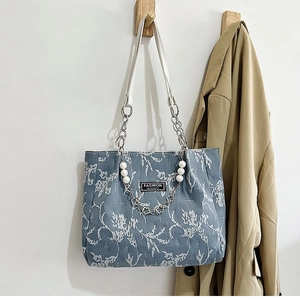 Détail du sac cabas floral bleu clair avec chaîne argentée et breloques en perles