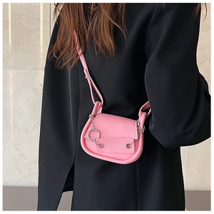 Détail d'un mini sac selle rose avec chaîne argentée porté sur un blazer noir pour femme