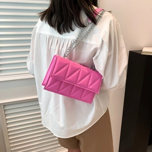 Sac à bandoulière rose matelassé avec chaîne porté par un mannequin dans un intérieur