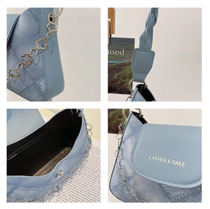 Detail of blue denim underarm bag with flower chain strap and woven top handle