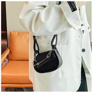 Détail d'un mini sac selle en cuir noir avec chaîne argentée élégante et bandoulière fashion
