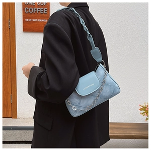 Détail du sac sous l'aisselle bleu clair avec design patchwork et bandoulière tressée