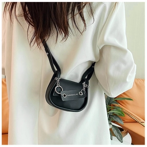 Détail d'un mini sac à bandoulière noir avec chaîne argentée et accents d'anneaux métal