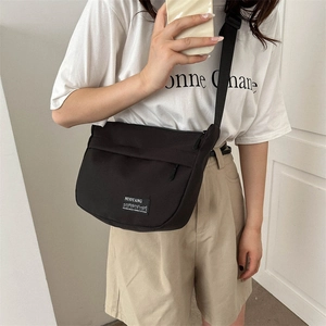 Minimalist black canvas crossbody bag for women with adjustable strap shown on model